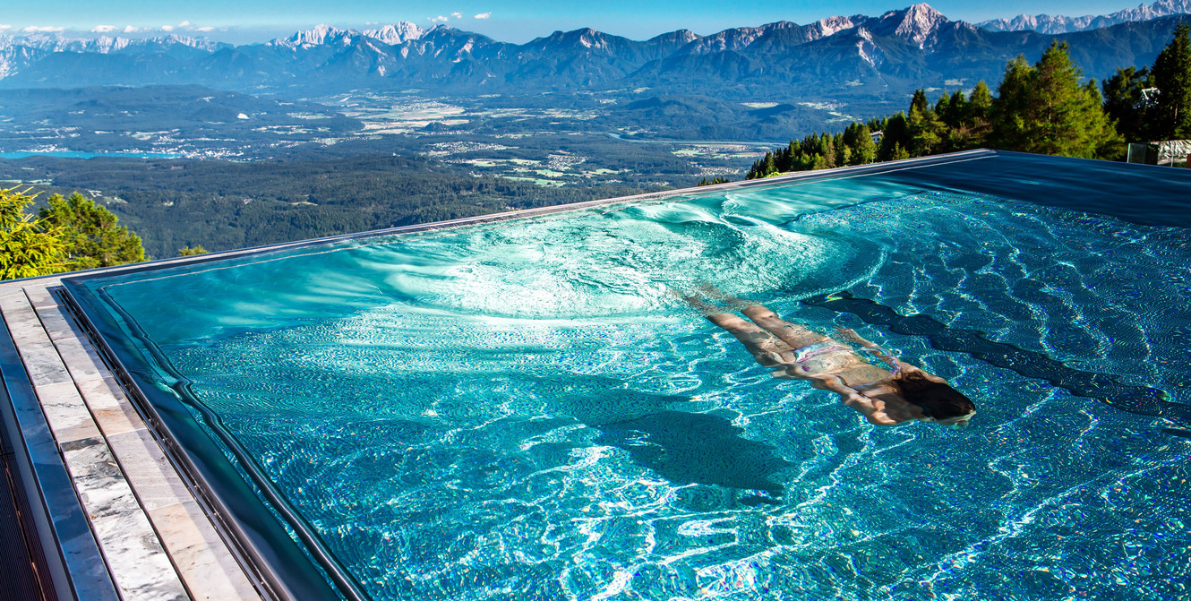 Frau schwimmt im Infinity Pool im Hotel Feuerberg in Kärnten