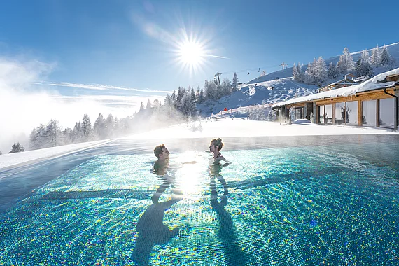 Ein Pärchen im Unendlichpool genießt den sonnigen Wintertag