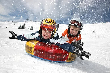 Kinder beim Tubing im Winter im Winterurlaub in Kärnten
