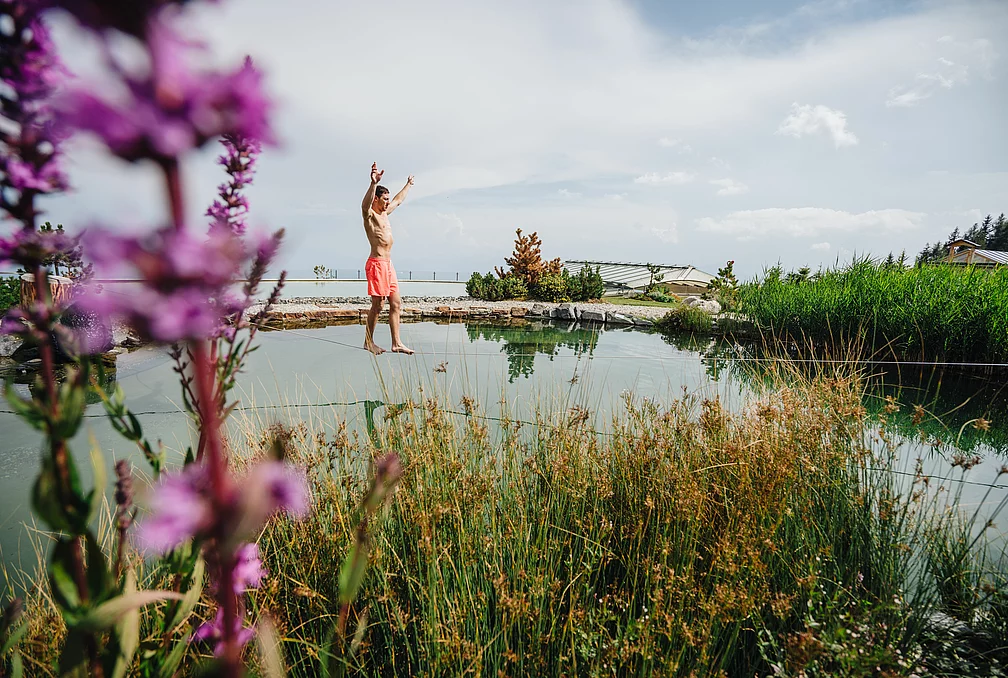 Slackline & Klettern Mann über einem See auf einer Slackline im Bergurlaub im Sommer auf der Gerlitzen Alpe in Kärnten