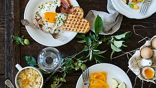 Frühstück mit Wafflen und Eiern angerichtet auf weißen Tellern im Mountain Resort Feuerberg in Kärnten