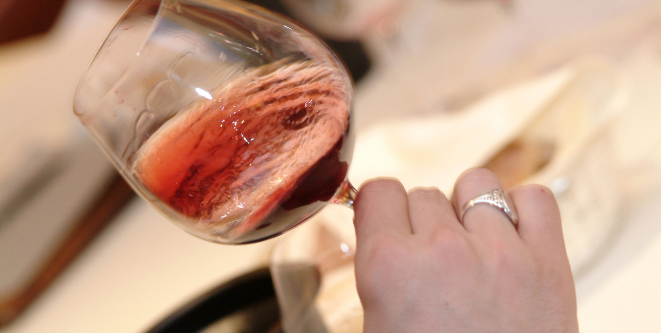 Hand schwenkt Rotweinglas