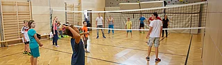 Family vacation Kinder und Teenager spielen Volleyball in der Indoor Kletterhalle bzw. Sporthalle des Mountain Resort Feuerberg im Bergurlaub in Kärnten