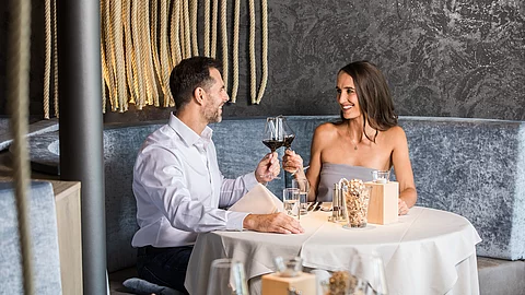 Zwei Personen genießen einen Rotwein im Restaurantbereich