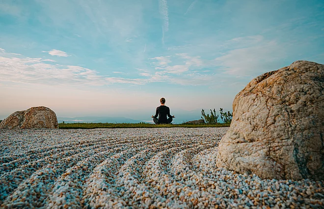 Eine Person in Meditationsposition mit Blick auf die Weite
