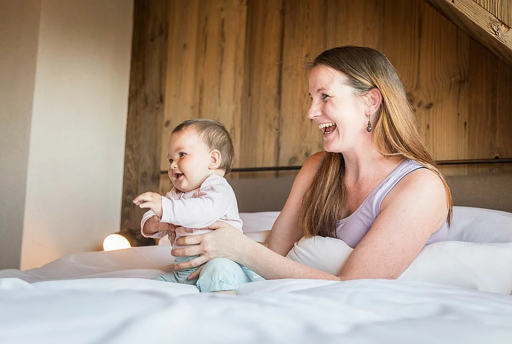 Children's discounts Mutter und Babyim Bett in einer der Familiensuites und Chalets im Familienhotel Feuerberg in Kärnten