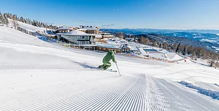 Ein Skifahrer fährt die Piste hinunter mit Blick auf das Mountain Resort.