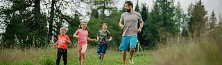 Ein Vater mit seinen Kindern beim Fußballgolf spielen
