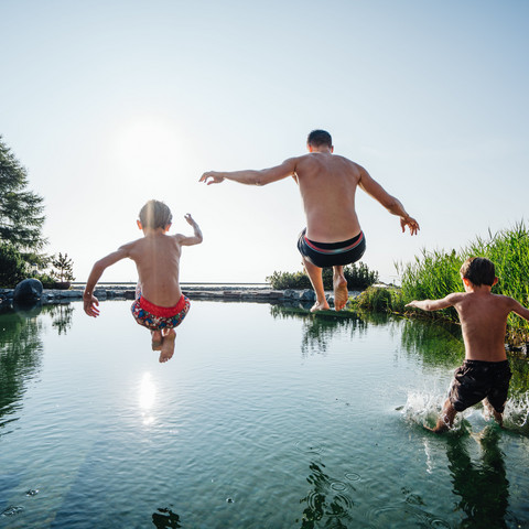 Kinder springen im Sommer in den Almsee des Family Spa Wellnesshotel Feuerberg in Kärnten