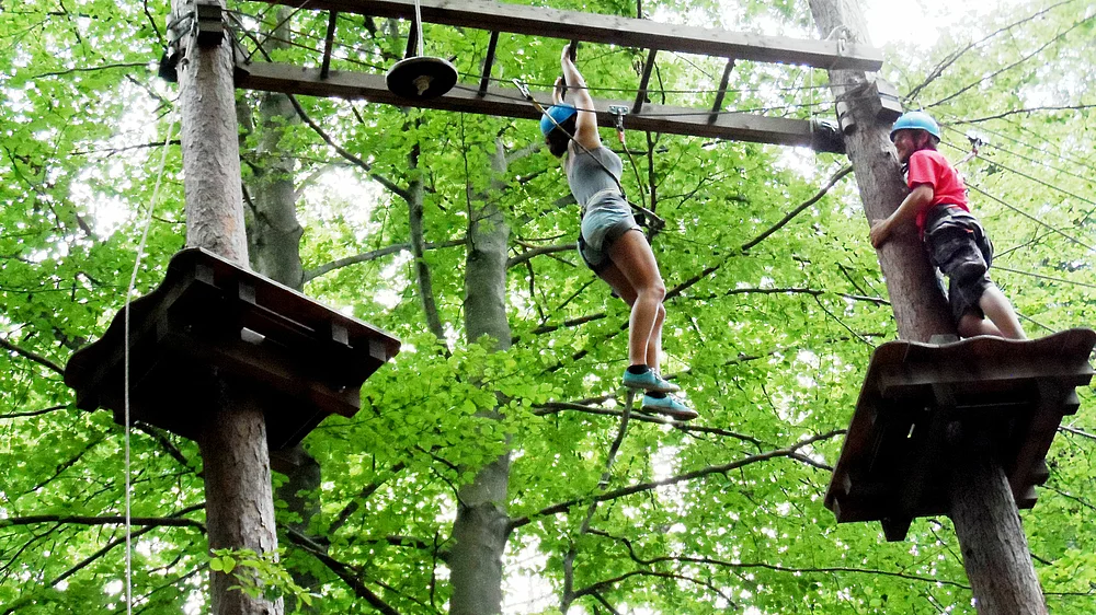 Teenager und Mann auf einem Hochseilgarten im Wald im Urlaub in Kärnten