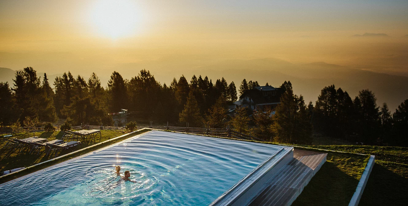 11 Pools / 1 Naturbadesee Paar schwimmt im Infinity Pool im Wellnesshotel Feuerberg auf der der Gerlitzen Alpe in Kärnten