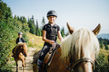 Mädchen reitet auf Pferd durch die Landschaft im Familienurlaub in Kärnten