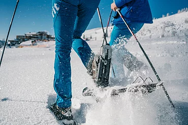 Mann und Frau beim Schneeschuhwandern durch eine verschneite Landschaft im Wellness- und Winterurlaub in Kärnten