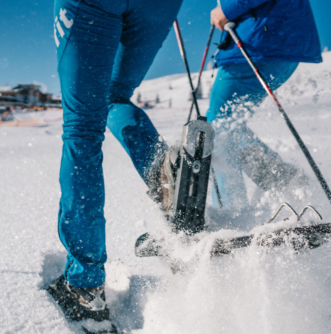 Mann und Frau beim Schneeschuhwandern durch eine verschneite Landschaft im Wellness- und Winterurlaub in Kärnten