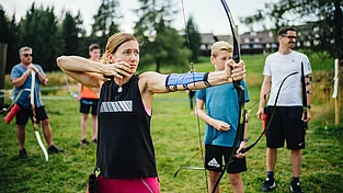 (c) Mountain Resort Feuerberg_Teens_Bogenschießen_Martin_Hofmann Mädchen beim Bogenschießen im Familienurlaub mit Kinderbetreuung in Kärnten