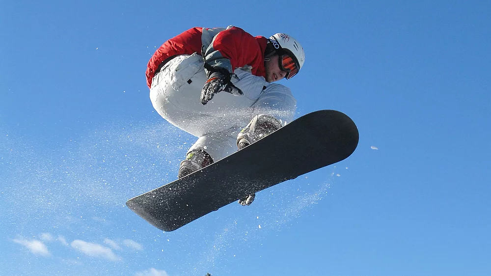 Snowboarder springt über einen Schneehaufen im Skiurlaub in Kärnten