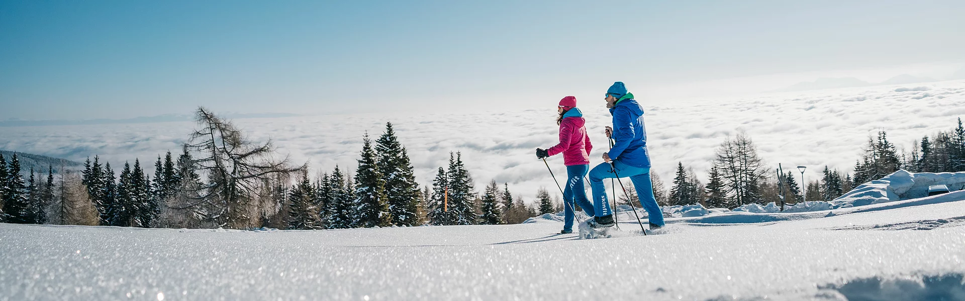Mann und Frau beim Schneeschuhwandern durch eine verschneite Landschaft im Wellness- und Winterurlaub in Kärnten