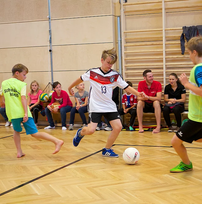 Kinder und Teenager spielen Fußball in der Indoor Kletterhalle bzw. Sporthalle des Mountain Resort Feuerberg im Bergurlaub in Kärnten