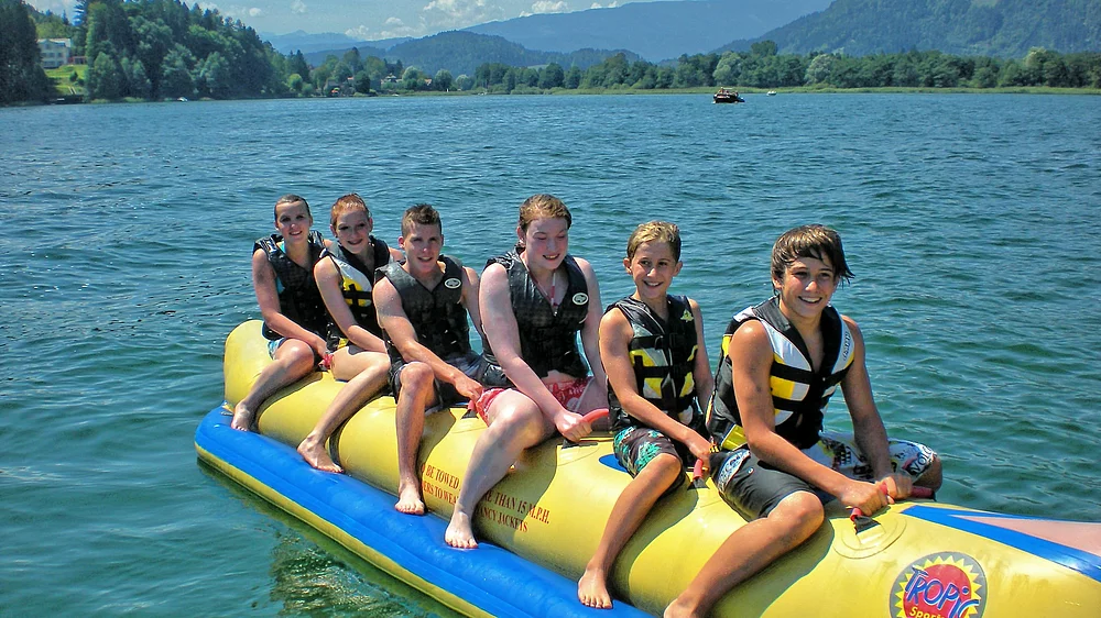 Jugendliche Teenager auf einer Banane im Ossiacher See im Urlaub in Kärnten
