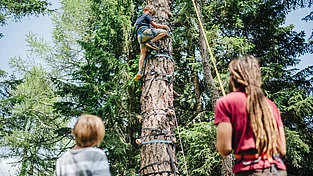 (c) Mountain Resort Feuerberg_Kinderbetreuung_Klettern_Martin_Hofmann Kinder beim Klettern im Wald im Familienurlaub in den Bergen im Mountain Resort Feuerberg