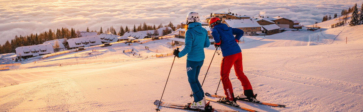 Skifahrer auf der Gerlitzen Alpe über dem direkt an der Piste gelegenen Skihotel Feuerberg in Kärnten