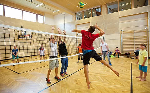 Kinder und Teenager spielen Volleyball in der Indoor Kletterhalle bzw. Sporthalle des Mountain Resort Feuerberg im Bergurlaub in Kärnten