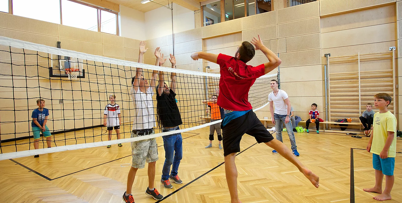 Kinder und Teenager spielen Volleyball in der Indoor Kletterhalle bzw. Sporthalle des Mountain Resort Feuerberg im Bergurlaub in Kärnten