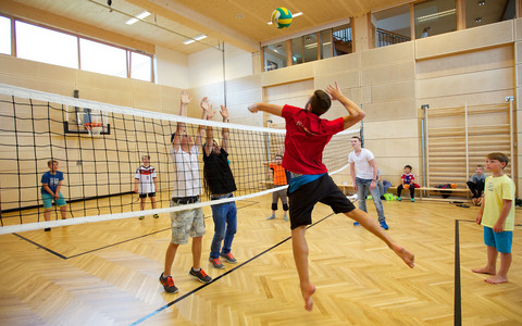Kinder und Teenager spielen Volleyball in der Indoor Kletterhalle bzw. Sporthalle des Mountain Resort Feuerberg im Bergurlaub in Kärnten